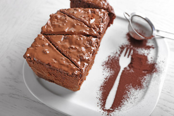 Delicious sliced chocolate cake with nut cream on white plate, close up