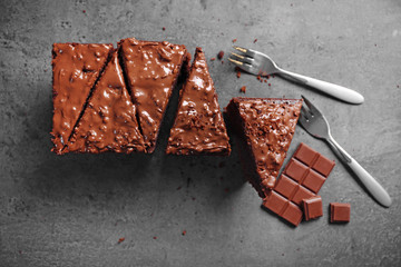 Tasty sliced cake with chocolate and forks on grey background, close up