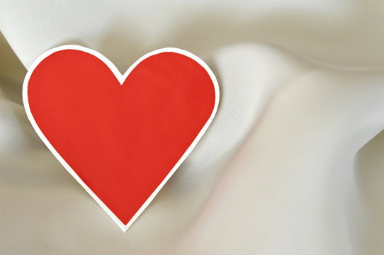 Valentine's red paper heart on white silk background