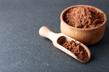 Bowl with aromatic cocoa powder on grey background, close up