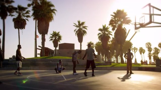 Slow motion shot of men playing basketball near Venice Beach, California filmed in slow motion