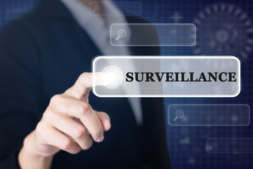 Businessman pressing a SURVEILLANCE concept button. Can be used in advertising.