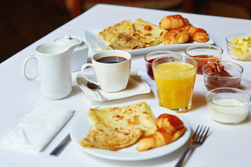 Breakfast with orange juice, pastry, pancakes and coffee