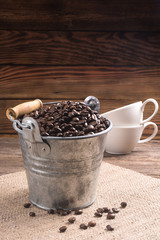 coffee bean in zinc bucket and cups on wooden background/cloth sack