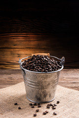 Fototapeta na wymiar coffee beans in zinc bucket on wooden background/cloth sack
