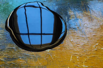 Oil spill on orange and blue work table with window reflection 