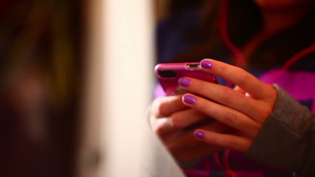 Girl on a trail with purple nails using her phone.