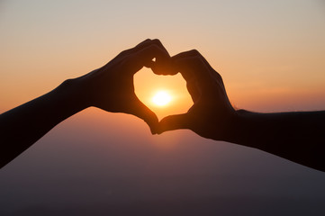 Lovers couple hands in Valentine' s heart with sunset background
