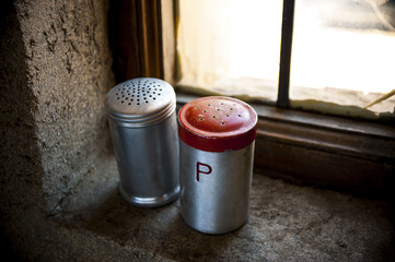 Salt and pepper shaker with red top on windowsill 