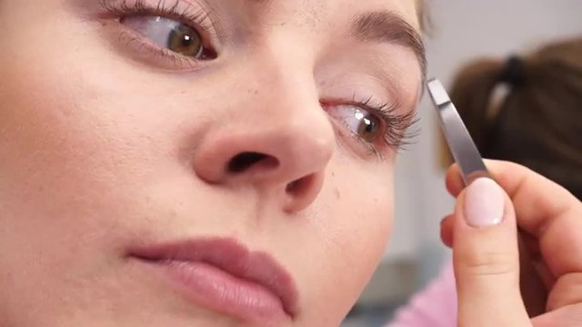 Woman tweezing eyebrows plucking with tweezers 4K