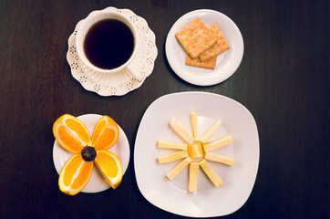Elegant breakfast concept seen from above, coffee cup, sliced oranges, crackers and cheese
