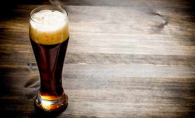 Glass of fresh beer on wooden table.