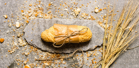 Ciabatta wrapped in paper with crumbs on a stone stand.