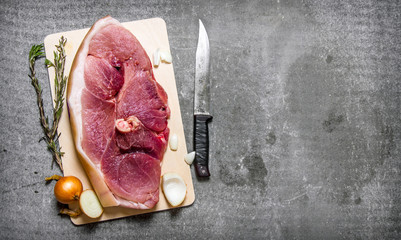 A piece of raw pork with spices and a cutting knife. - Powered by Adobe