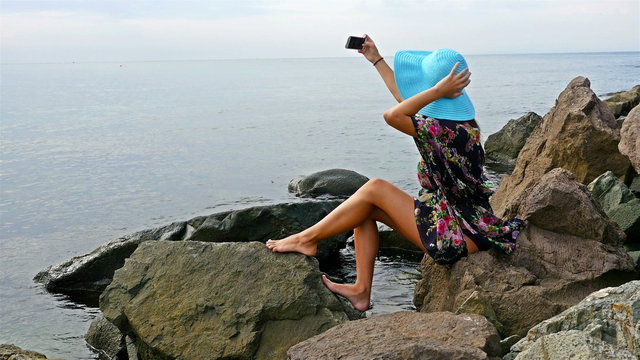 Young woman sitting on the rocky sea shore