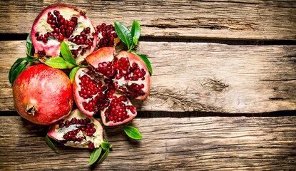 Fresh red pomegranate with leaves. On wooden background.