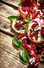 Fresh pomegranate with leaves . On wooden background.