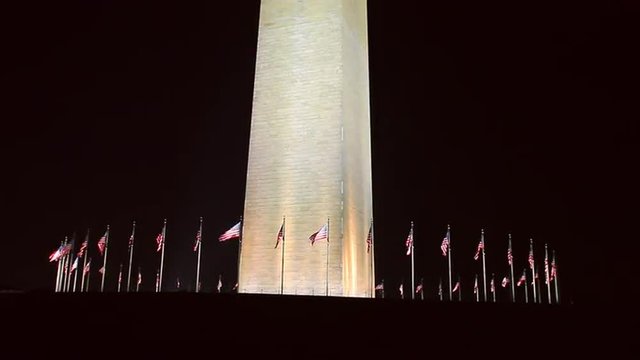 A static shot of the bottom of the Washington Monument against the darkness of the night.