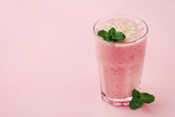 Berry smoothie or milkshake with oats decorated mint leaves on pink background, healthy and delicious breakfast