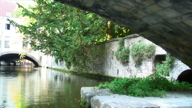 Going under a stone bridge on a canal in Bruges, Belgium.