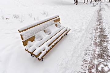 Lonely Bench in the Park Covered by Snow in Winter