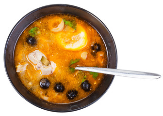 top view of Solyanka fish soup in bowl with spoon