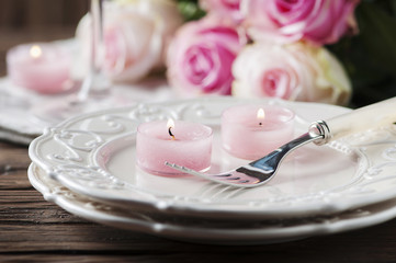 Pink candle and roses on the table