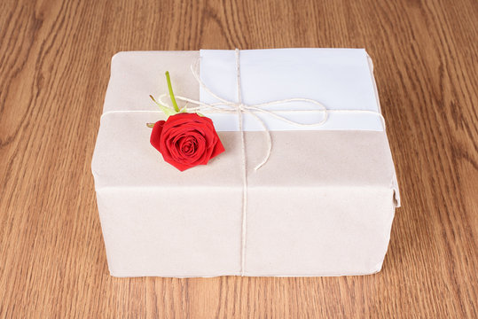 Red rose on gift package on wooden