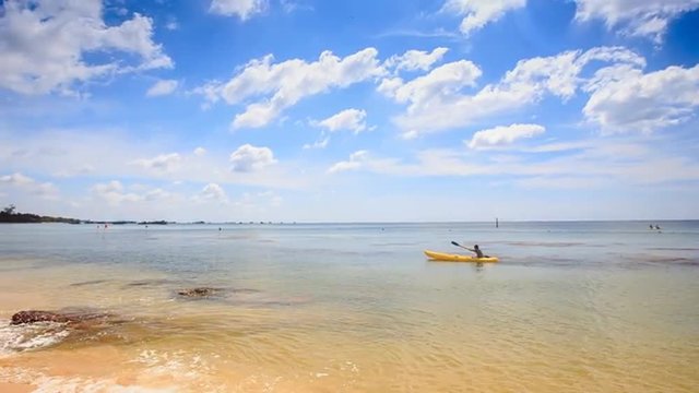 Guy Paddles Kayak along Shallow Transparent Sea