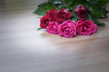 Bunch of roses on wooden surface with space for text