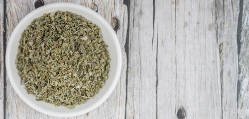 Marjoram herbs in white bowl over wooden background