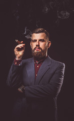 Stylish man in a suit smoking cigare.