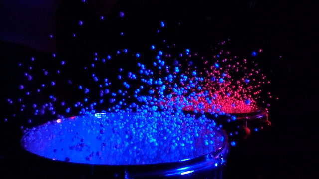 Close up of drums with styrofoam balls for special effect hit by unrecognizable guy in slow motion over black background