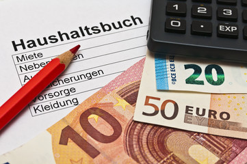 Haushaltsbuch, Geld und roter Buntstift 