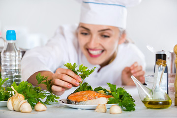 Professional chef decorating dish with salmon