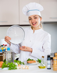 Happy female cook holding clock near prepared salmon