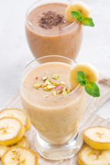 Banana and chocolate milkshake on white table, vertical