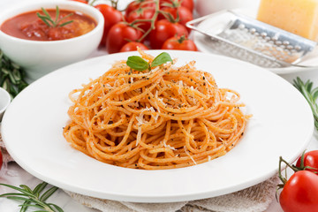 pasta with tomato sauce on a plate and ingredients, closeup