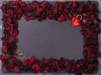 Background of red rose petals ,on a black background and wedding rings.Valentine's day.Marriage.Copy space.selective focus.