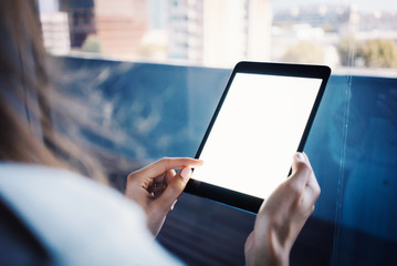 Girl holding her tablet on the blurred city background. Horizontal