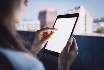 Girl touching screen of her tablet on the blurred city background. Horizontal