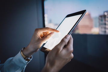 Girl touching screen of her tablet on the blurred city background. 