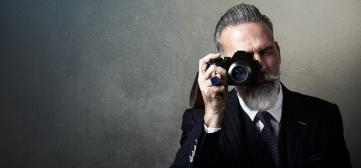 Portrait of bearded gentleman makes the photo on a retro camera. Wide