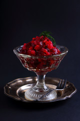 salad with beets and potatoes in a glass vase on a black background