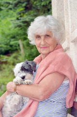 beautiful Senior smiling woman hugging her small white poodle dog in the mountain