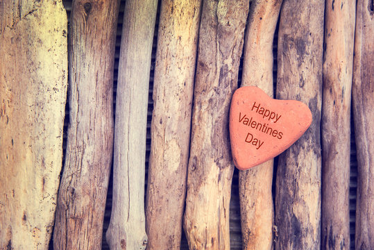 Happy Valentines Day, stone in the shape of a heart on wood background