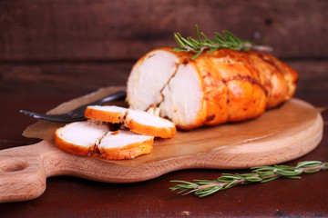 ham chicken breast baked with rosemary on a wooden cutting board