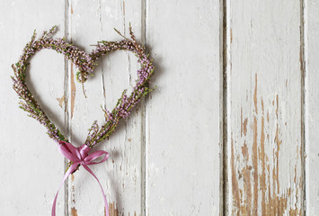 Heather (erica) door wreath in heart shape on wooden background