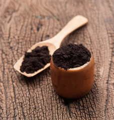 close up of a spoon and black powder on wood