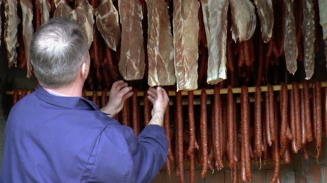 Worker checks smoked dry sausage and smoked meat.